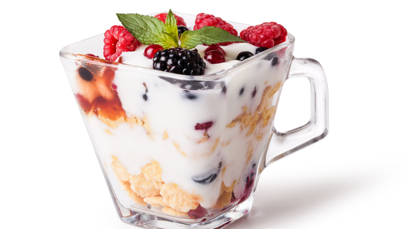 Хлопья с йогуртом и ягодами в стакане на белом фоне