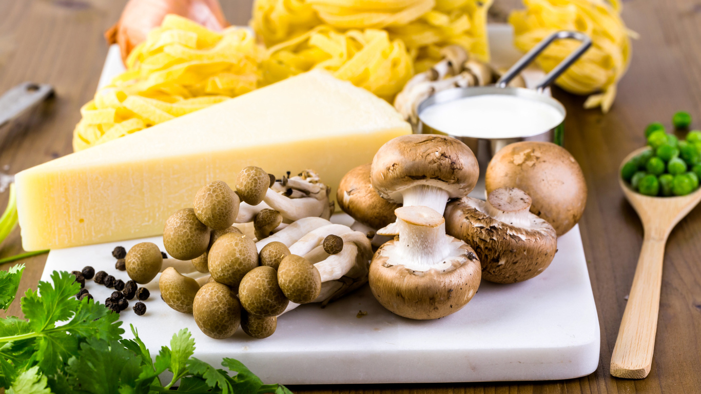 Грибы на разделочной доске с сыром, макаронами и зеленью