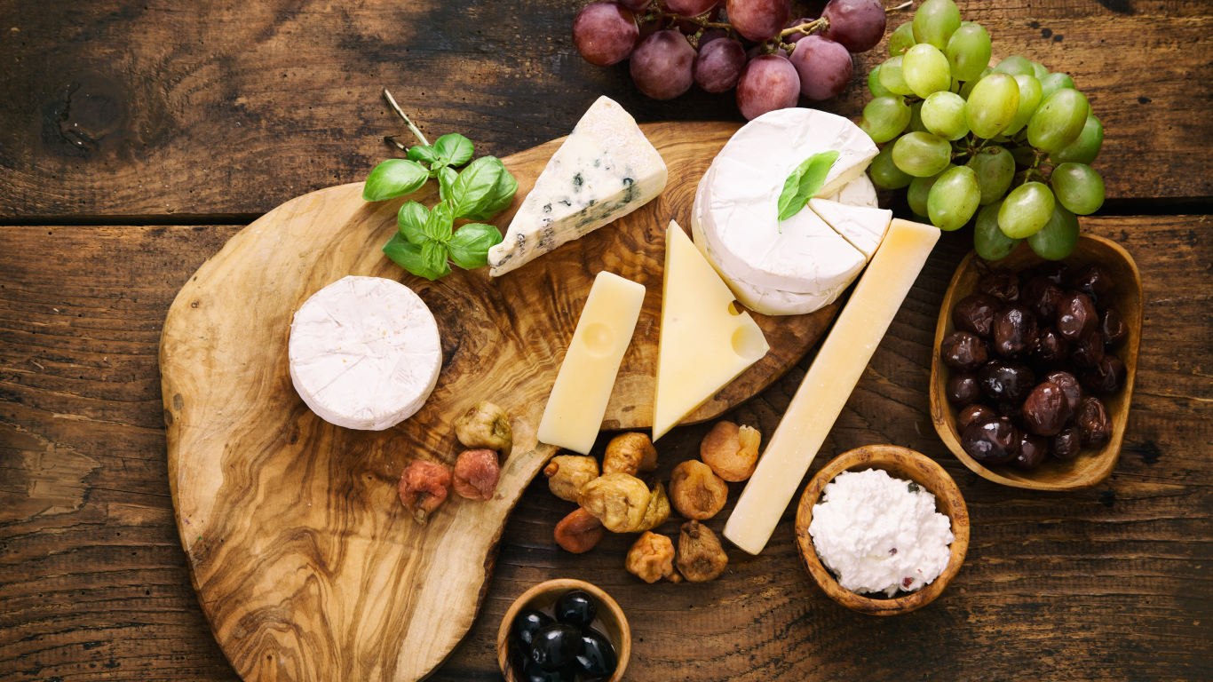 Кусочки сыра с виноградом и оливками на столе