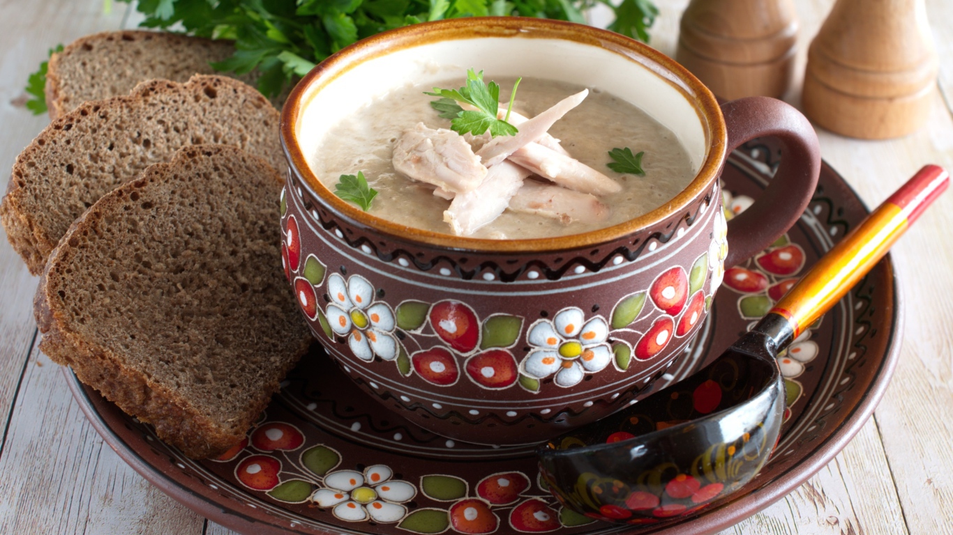 Суп с курицей в красивой тарелке на столе с черным хлебом