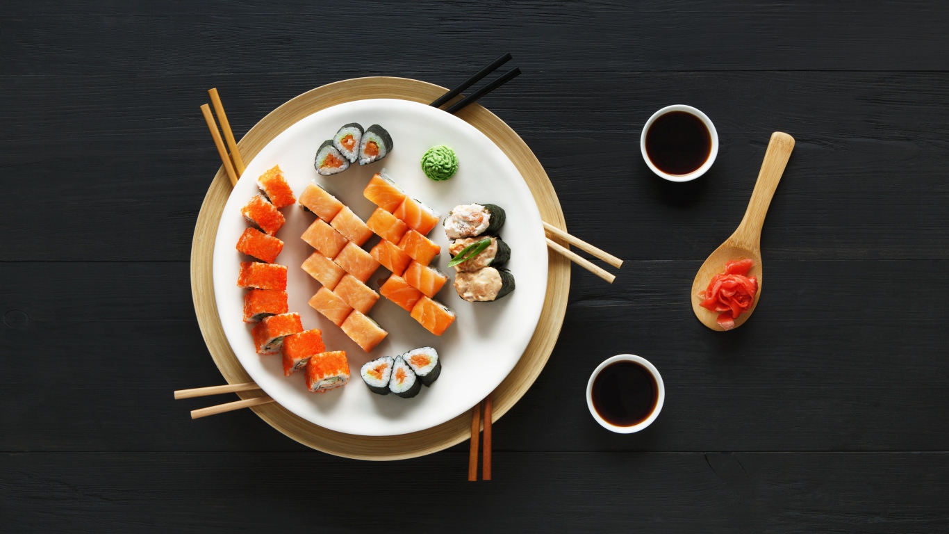 Суши и роллы на большой белой тарелке с соевым соусом