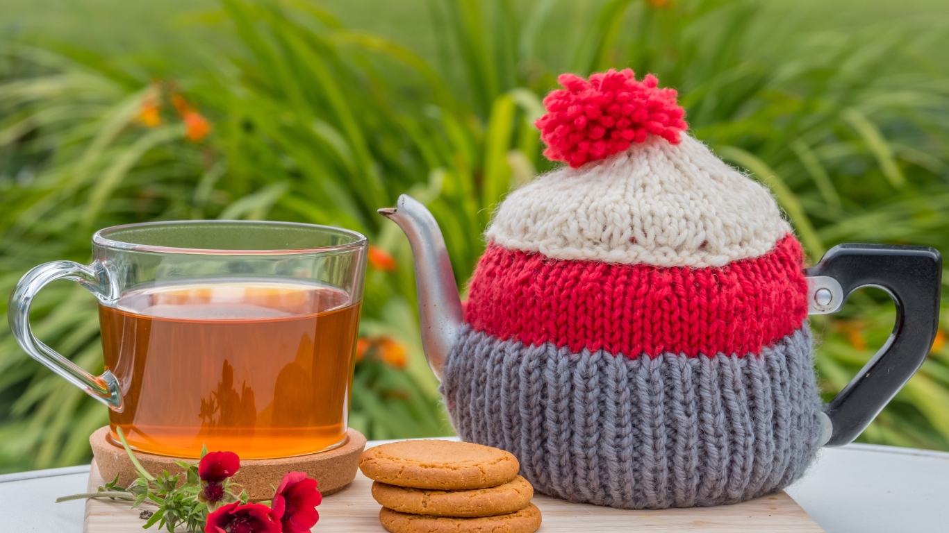 Чайник с чашкой чая на столе с печеньем и цветами