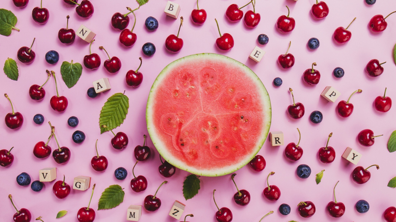 Половина арбуза с ягодами вишни и черники на столе