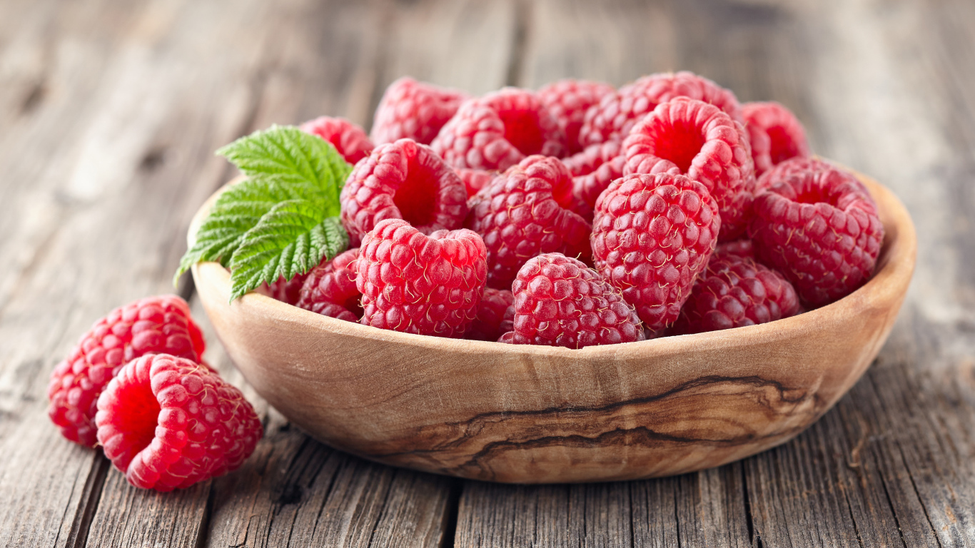 Крупные спелые ягоды малины в деревянной миске на столе