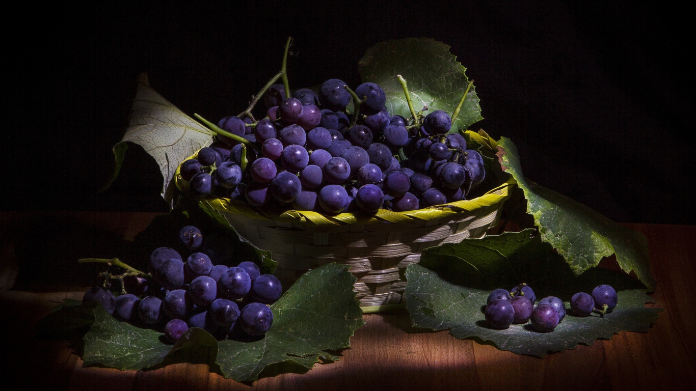 Круглый синий виноград в корзине на столе