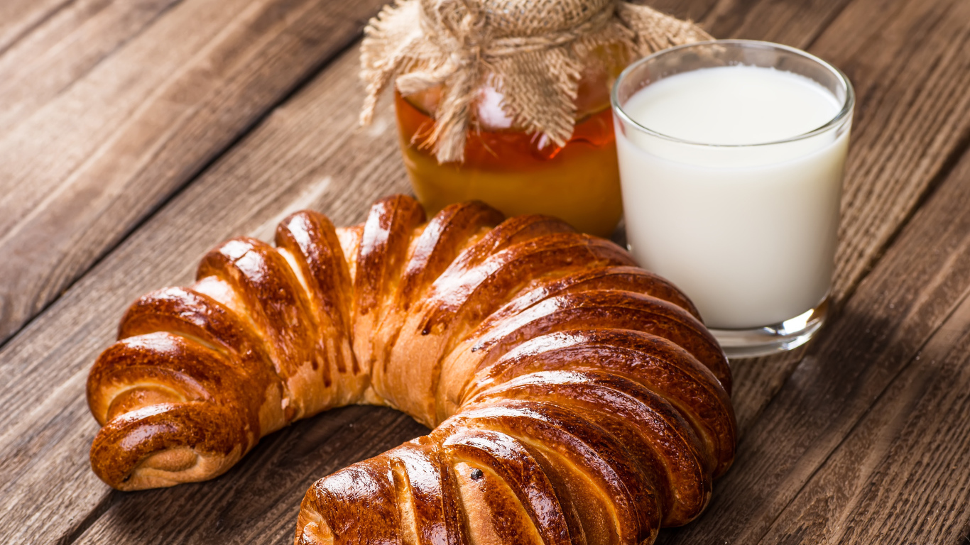 Свежая выпечка на столе с медом и стаканом молока