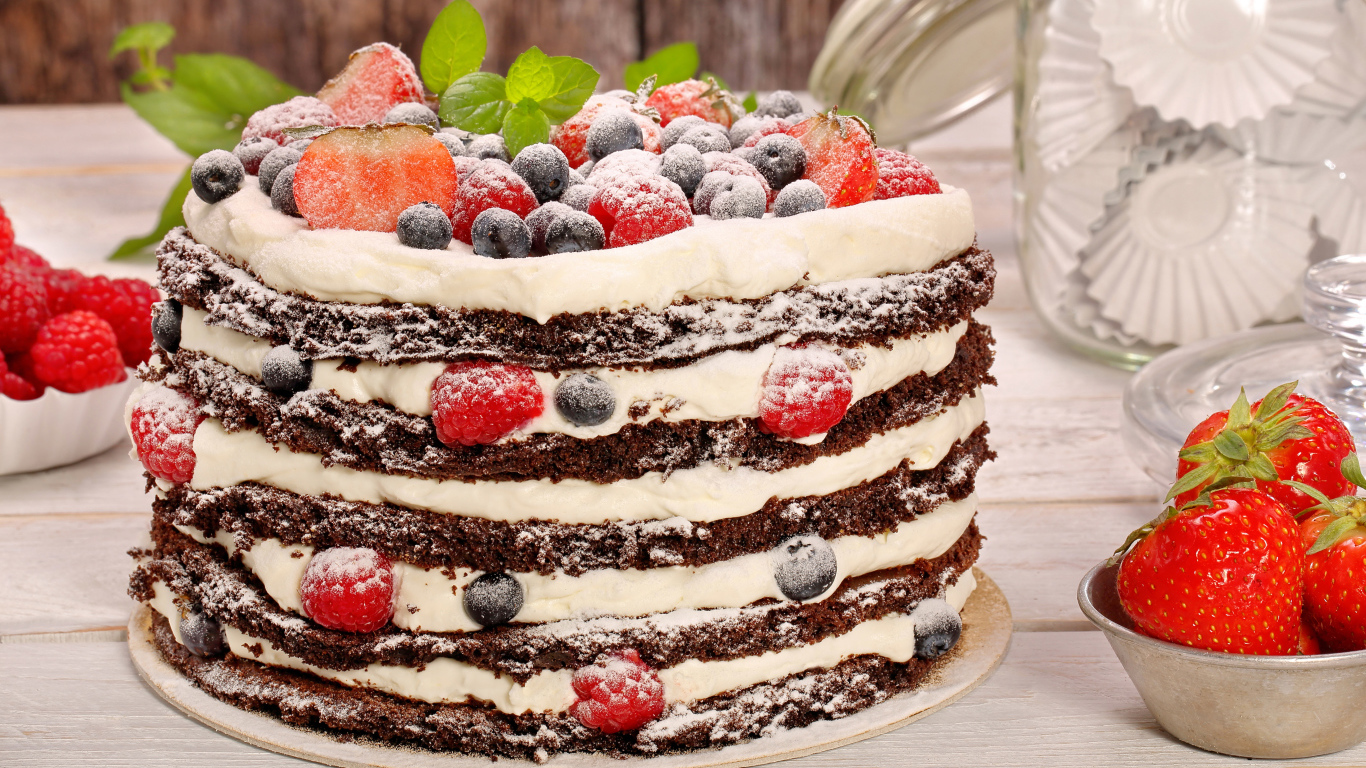 Аппетитный торт с кремом и ягодами посыпан сахарной пудрой