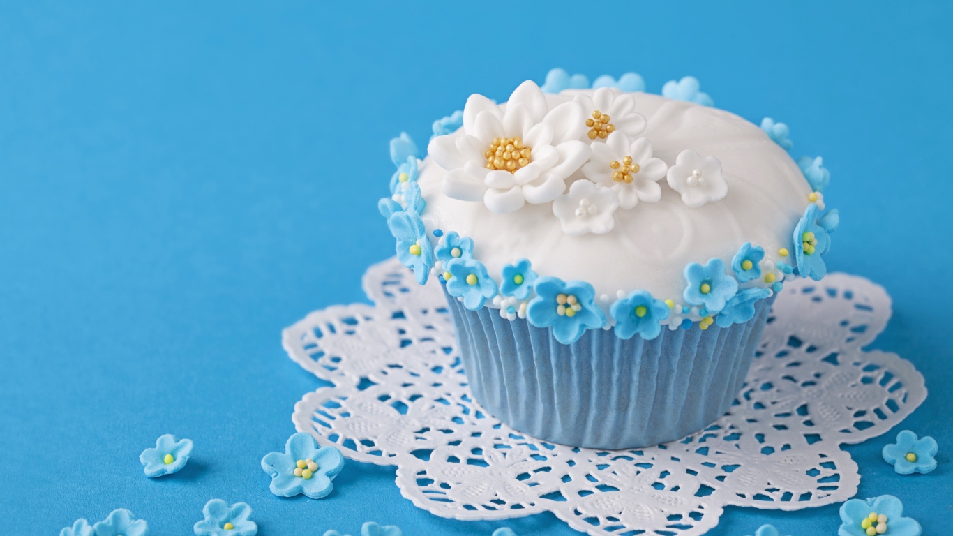 Аппетитный кекс украшен цветами на голубом фоне