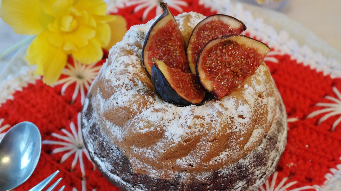 Кекс с инжиром и сахарной пудрой на столе с цветами