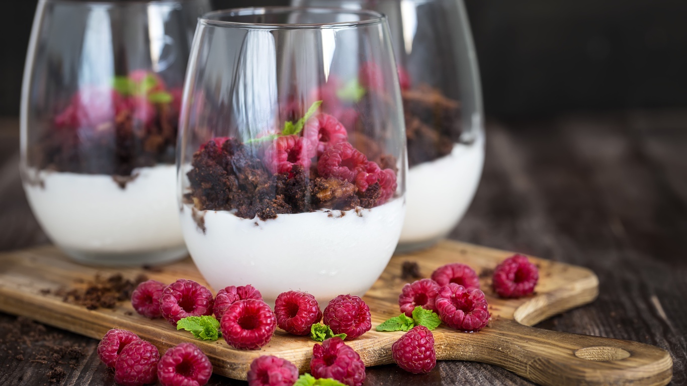 Десерт со сливками, шоколадом и свежей малиной в стеклянных стаканах