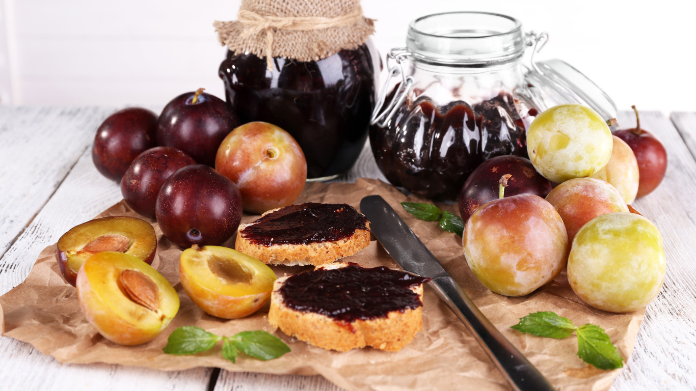 Свежие сливы и сливовый джем на столе 