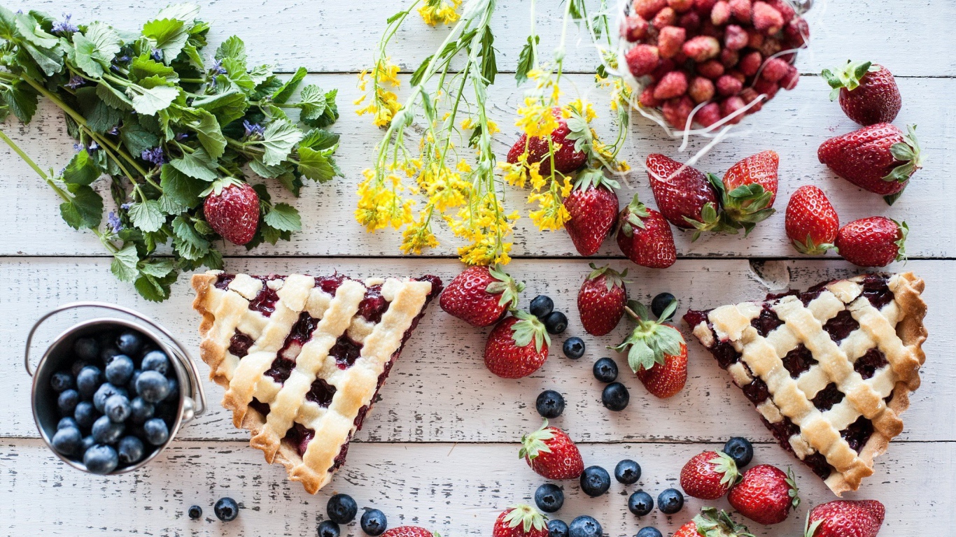 Кусочки пирога на столе с ягодами клубники и черники