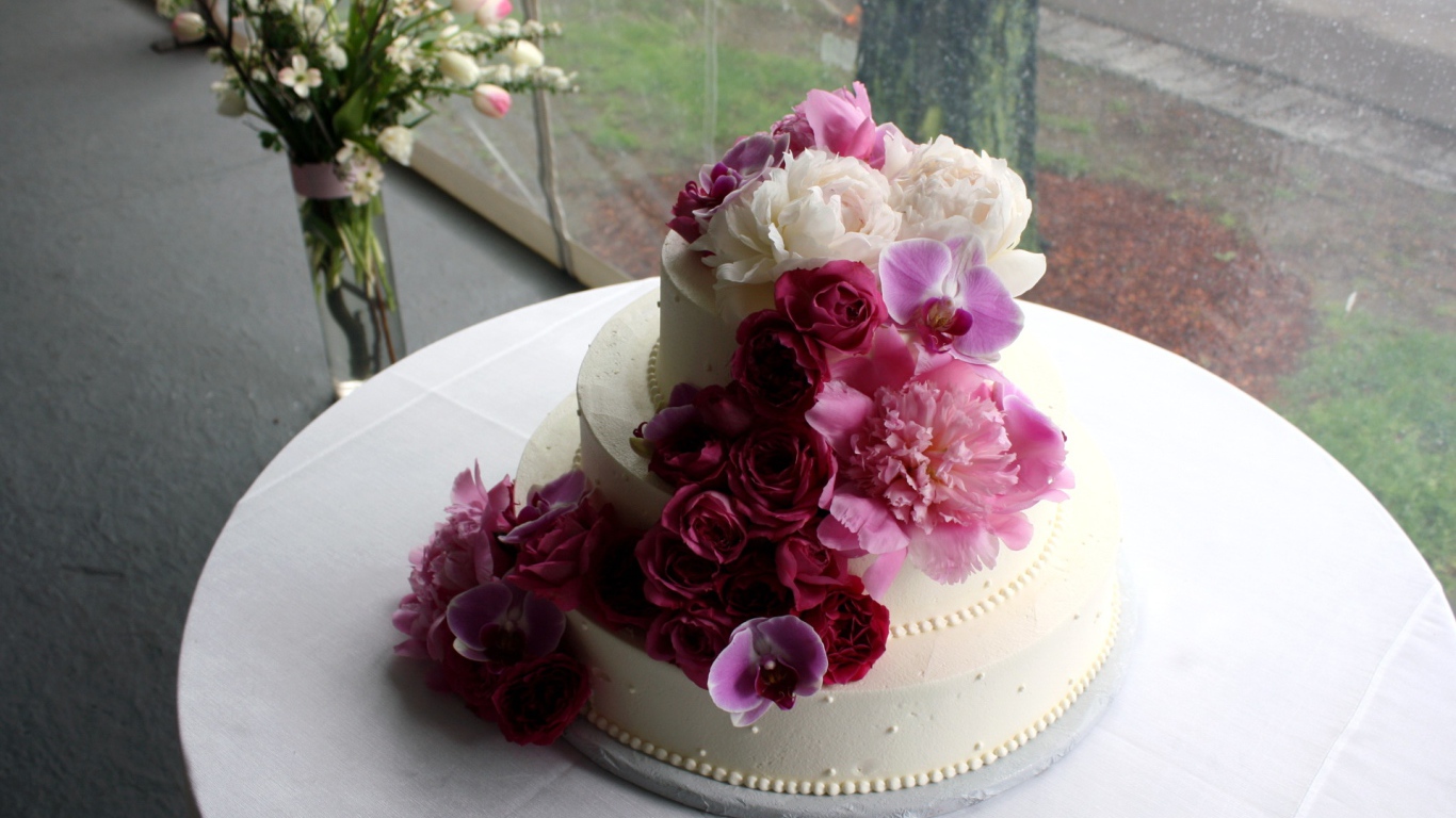 Большой свадебный торт украшен живыми цветами