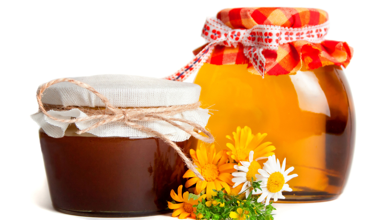 Две банки меда с цветами на белом фоне