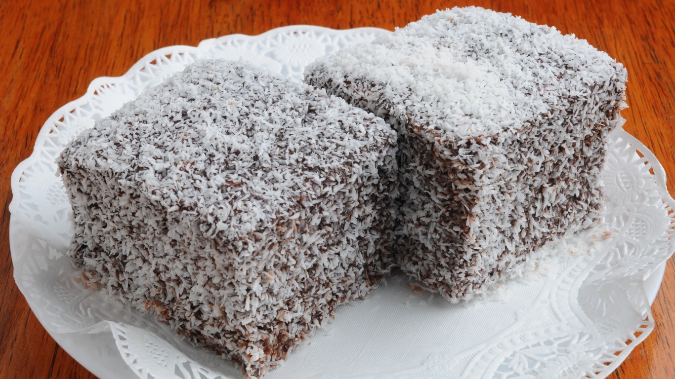 Два кусочка пирожного в кокосовой стружке на белой тарелке