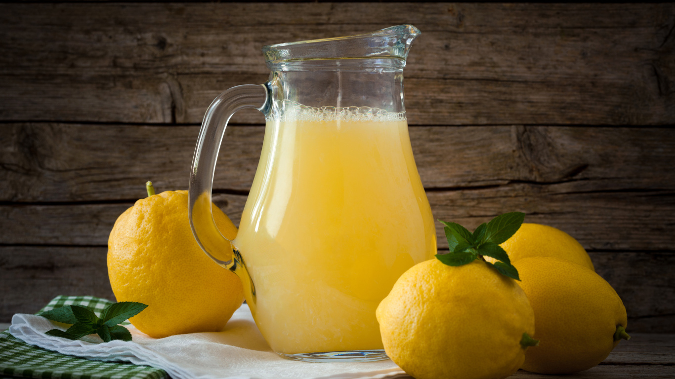 Свежевыжатый лимонад в стеклянном кувшине на столе