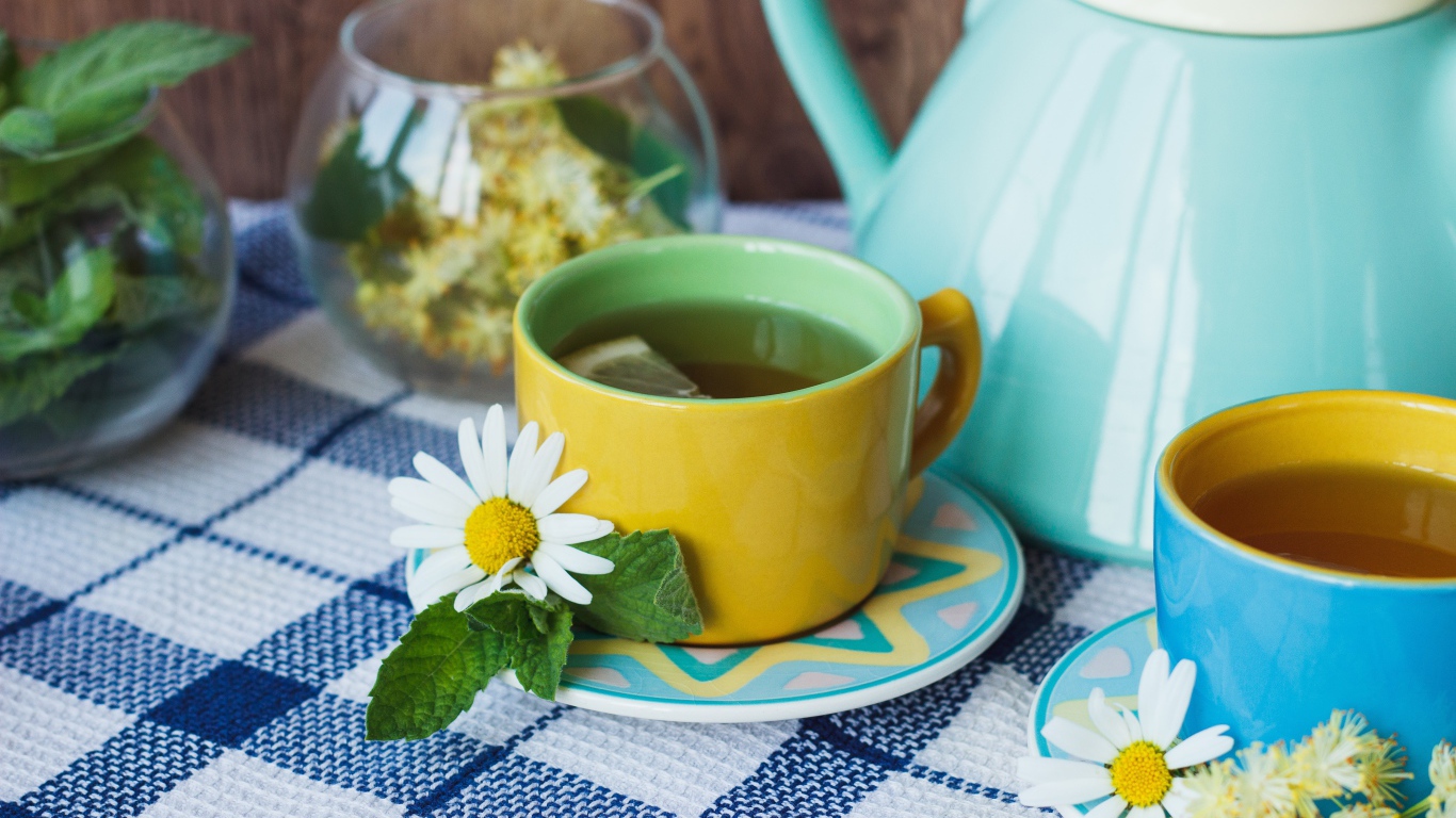 Чай с цветами ромашки в желтой чашке на столе