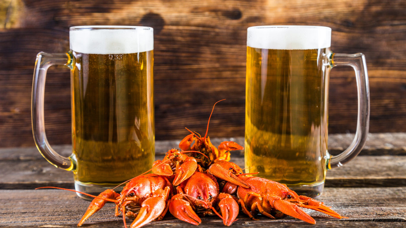 Два бокала пива с красными раками на столе