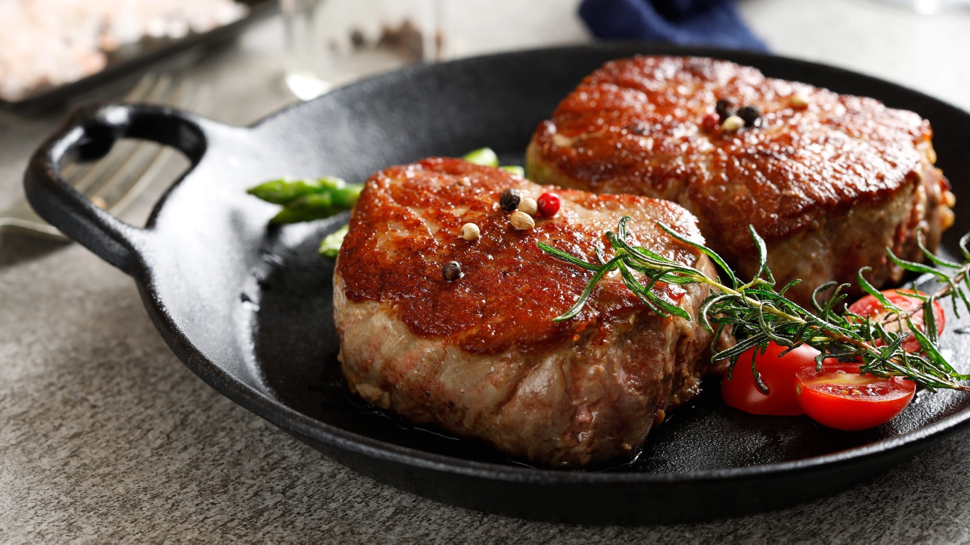 Два аппетитных сочных куска мяса с помидорами и розмарином