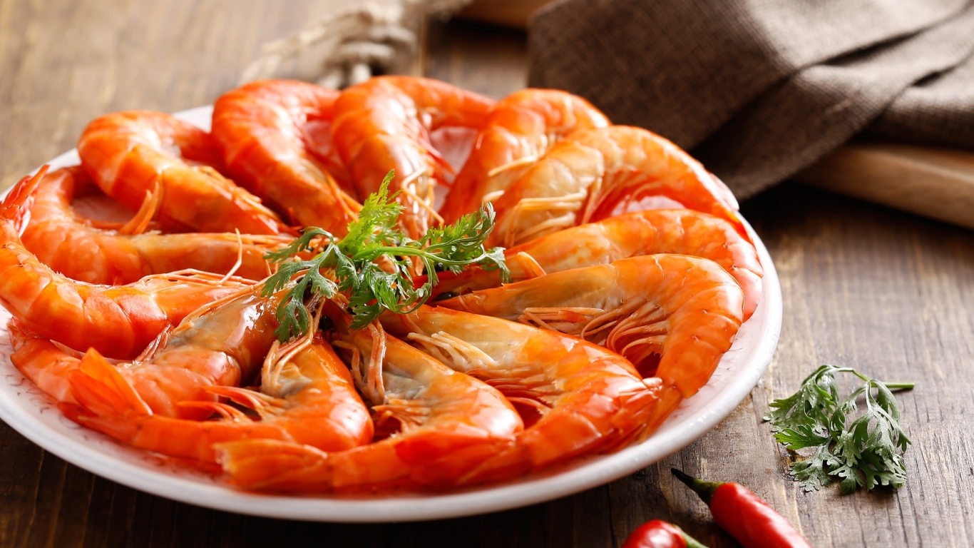 Аппетитные вареные креветки на тарелке с зеленью петрушки