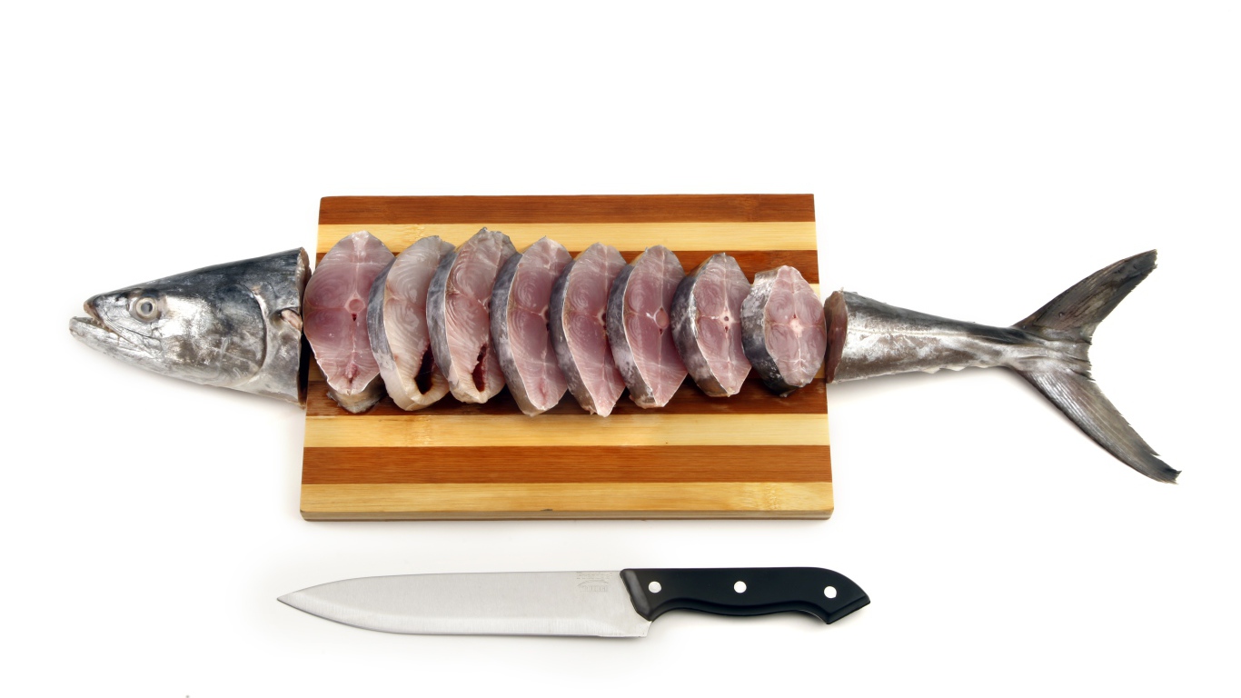 Свежая рыба кусочками на деревянной доске с ножом 