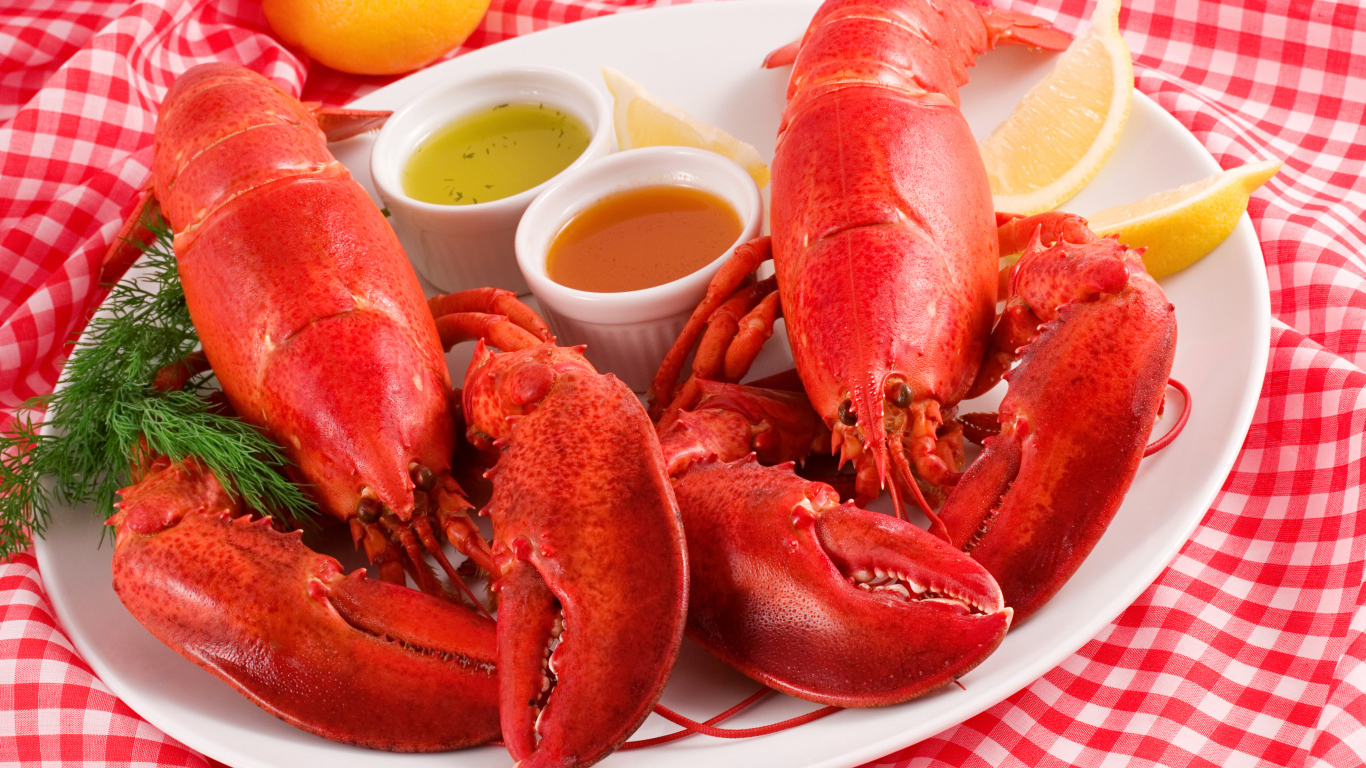 Два вареных омара на тарелке с соусом