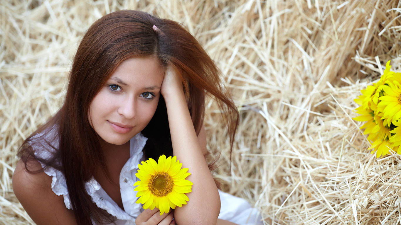 Милая девушка шатенка с цветком подсолнуха в руке