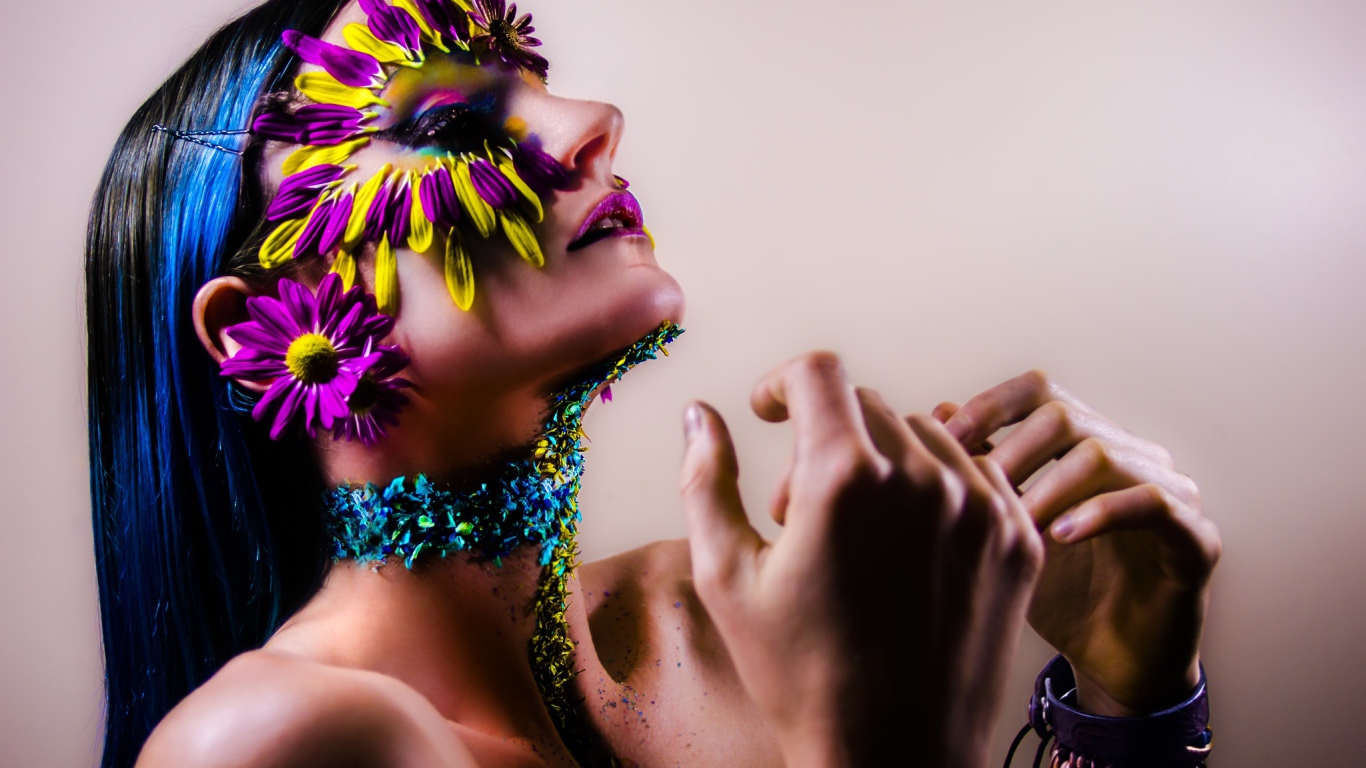 Девушка с украшенным лепестками цветов лицом и ярким макияжем