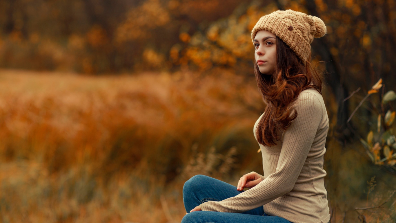 Молодая девушка в синих джинсах и теплой шапке