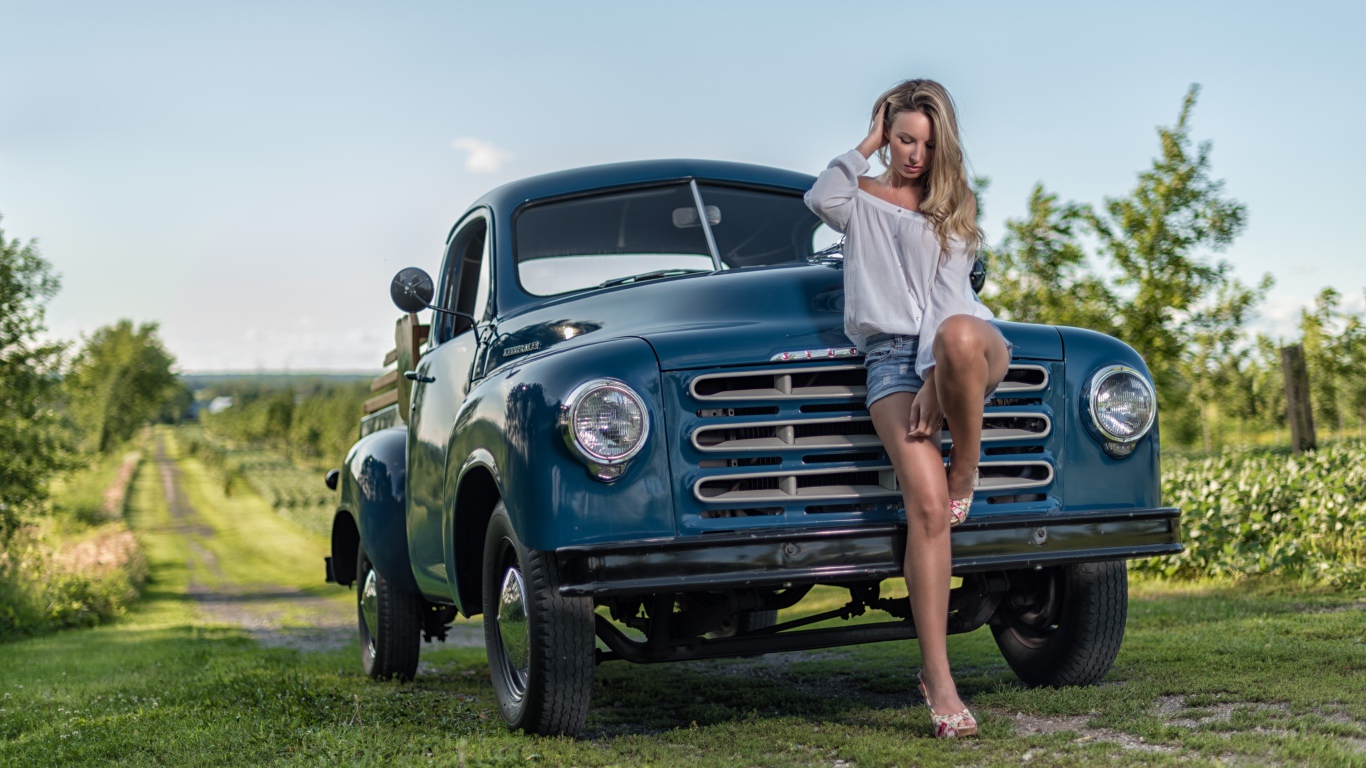 Молодая девушка стоит рядом с зеленым автомобилем Studebaker Pickup, 1953 года