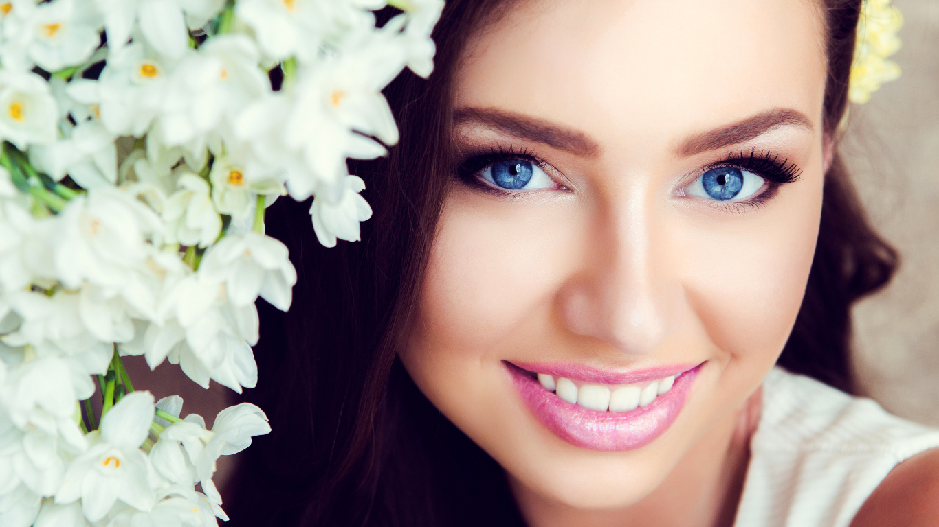 Красивая голубоглазая брюнетка с нежными цветами белой орхидеи