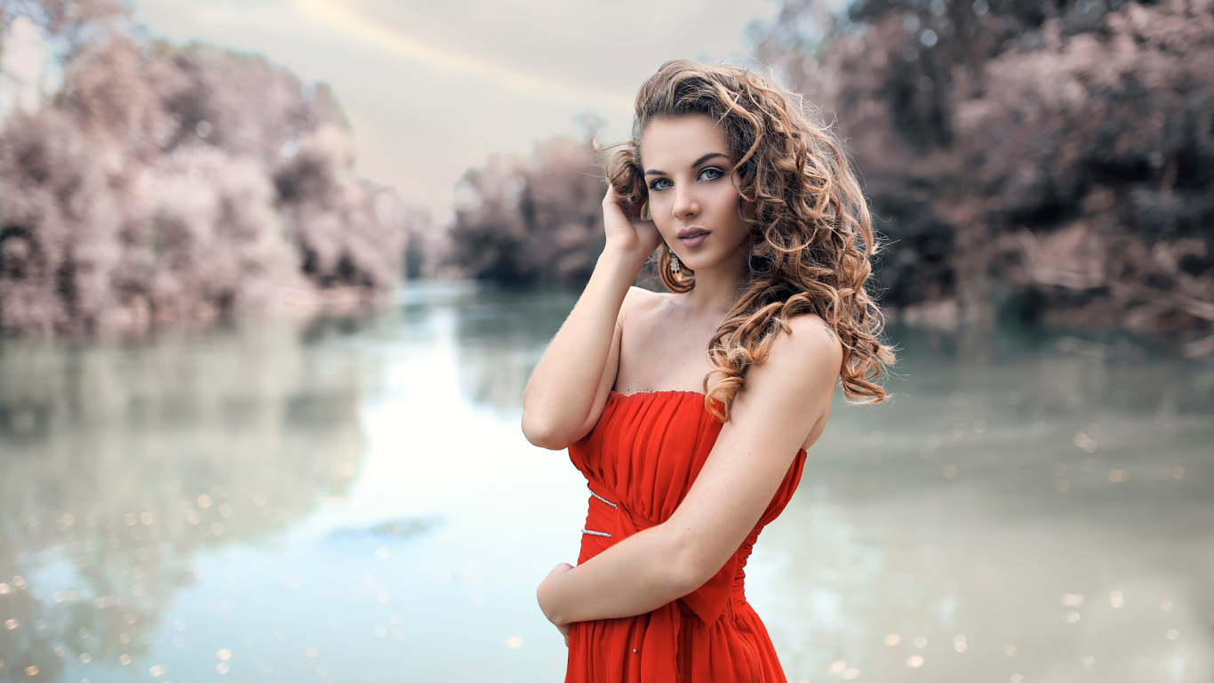 Красивая девушка брюнетка в красном платье у водоема