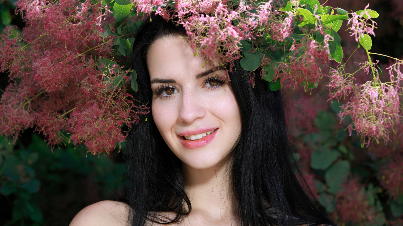Красивая брюнетка стоит у цветущей ветки