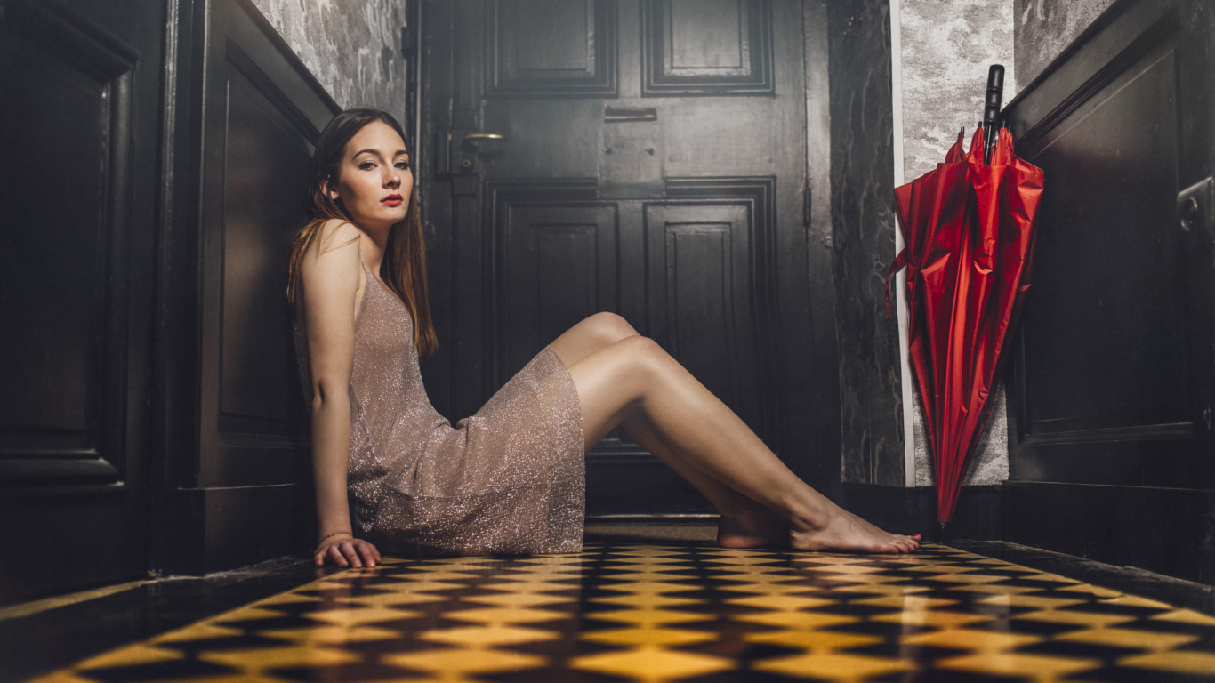 Красивая девушка модель с красным зонтом сидит на полу