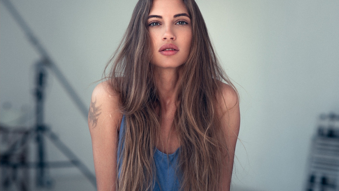 Девушка с длинными волосами и татуировкой на плече 