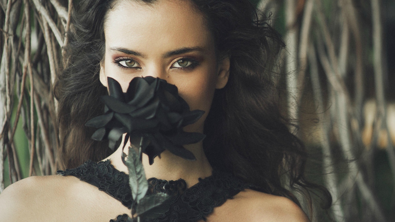 Зеленоглазая девушка брюнетка с черной розой в руках