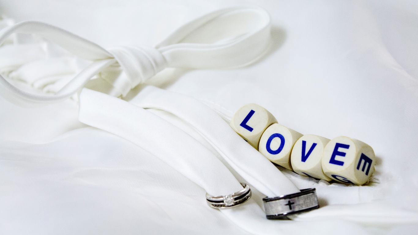 Два кольца перевязанные белой лентой и кубики с надписью любовь