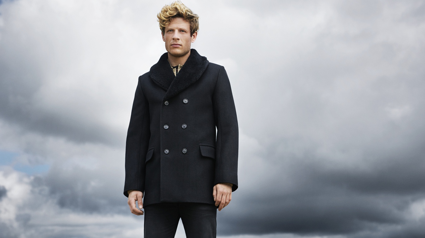 Актер Джеймс Нортон в черном пальто на фоне неба