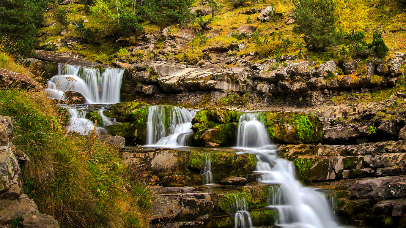 Быстрый ручей стекает по скале в осеннем лесу