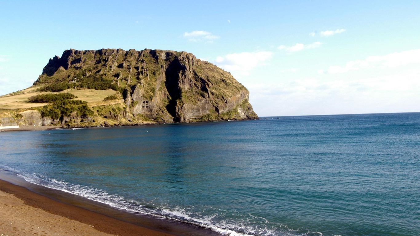 Гора на фоне спокойной воды моря под голубым небом
