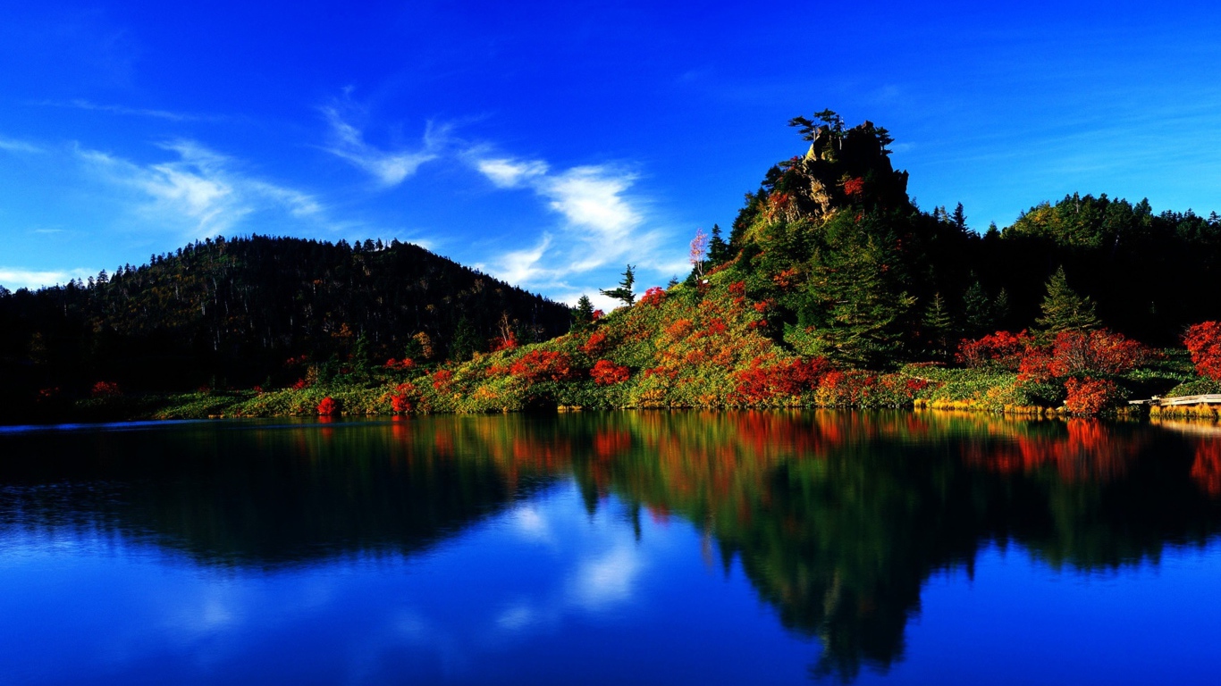 Голубое небо отражается в чистой воде озера 