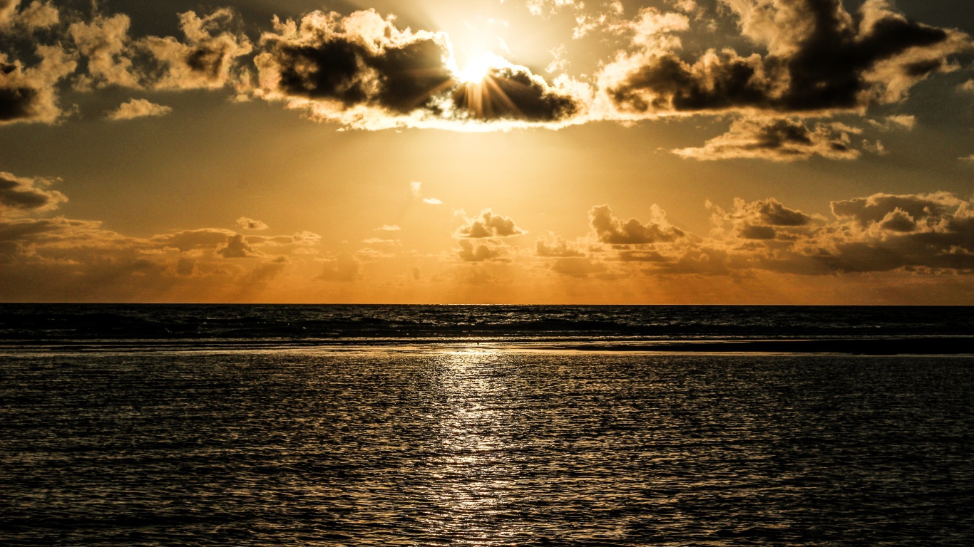 Солнечные лучи пробиваются сквозь облака над океаном