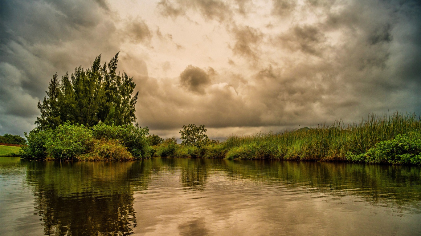 Облака над озером с покрыми зеленой травой берегами