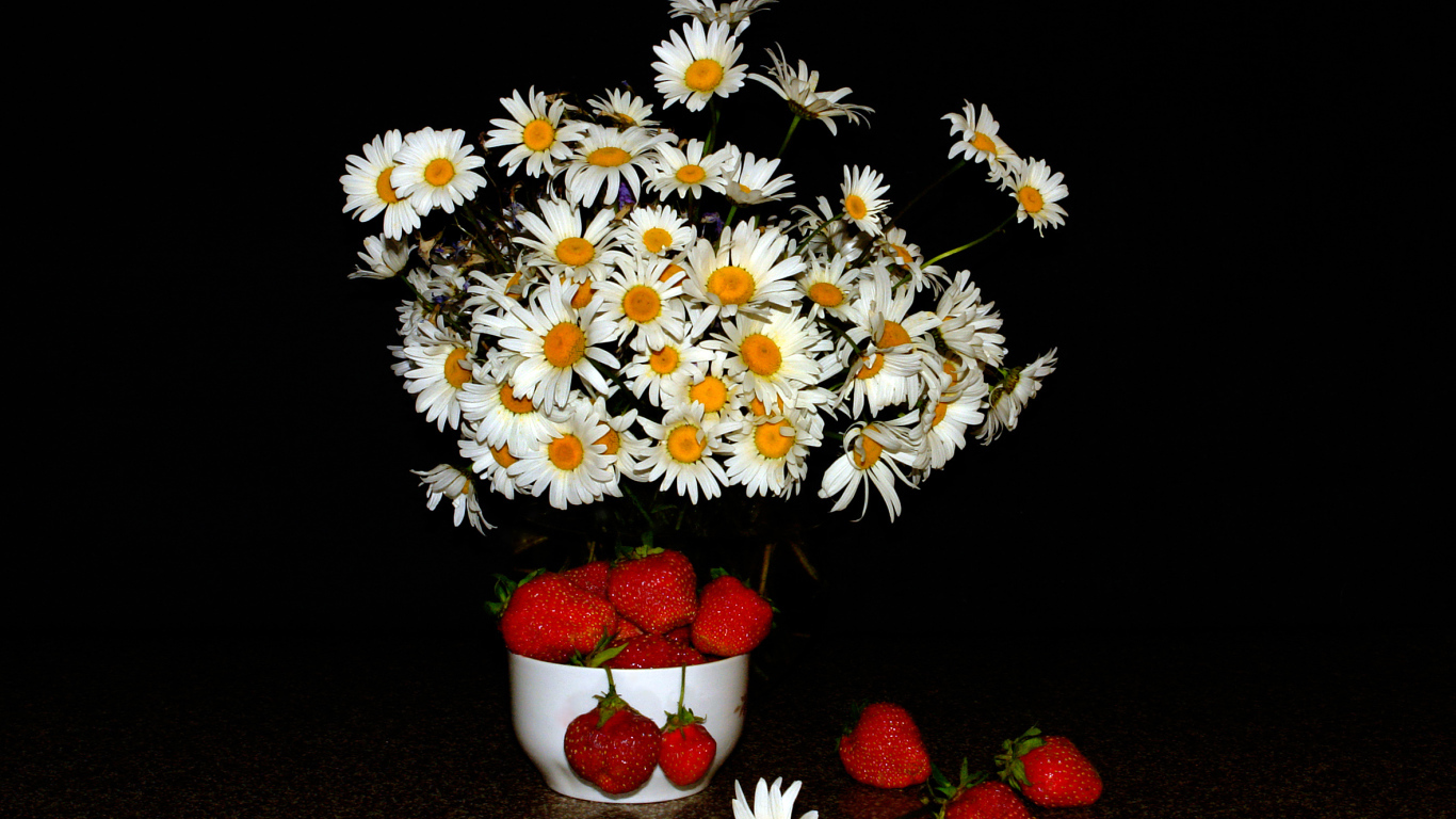 Белые полевые ромашки и клубника на столе на черном фоне