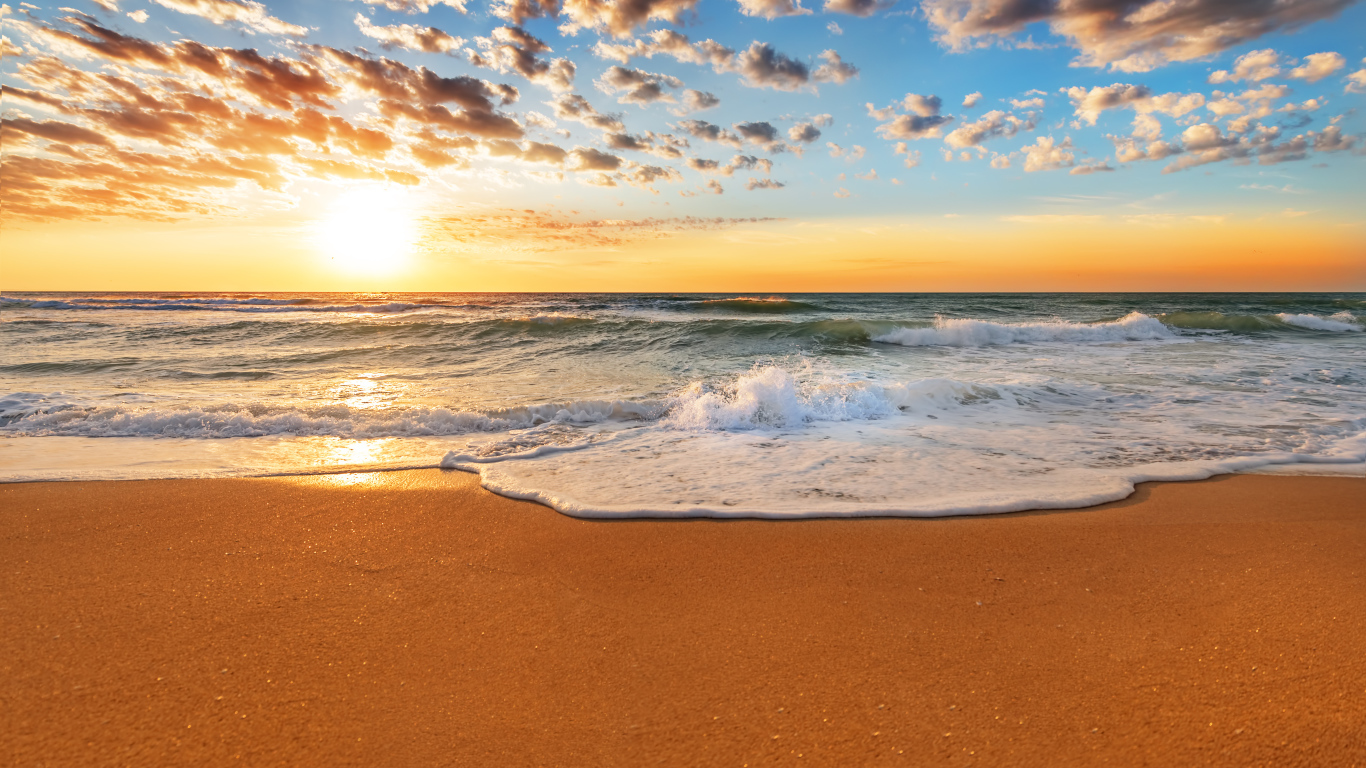 Волна омывает горячий желтый песок на берегу моря