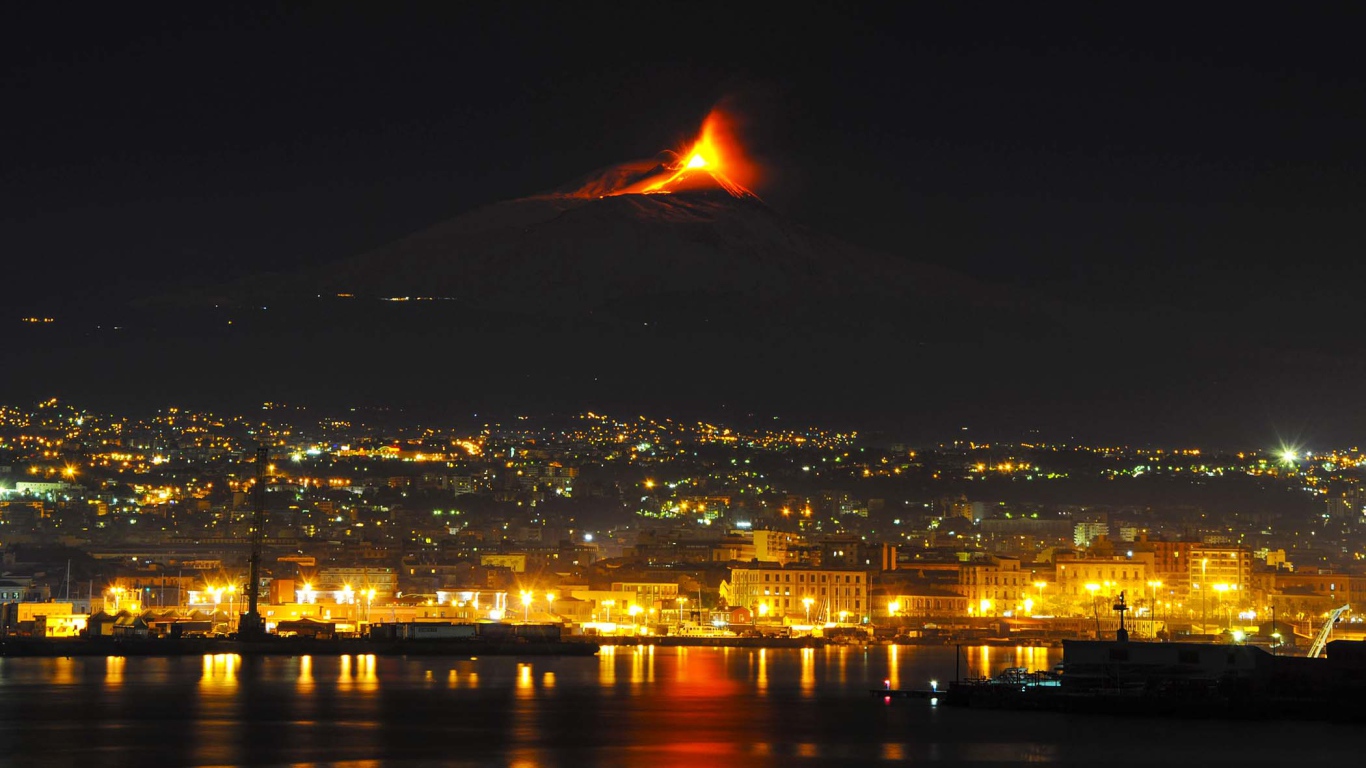 Пробуждение вулкана Этна на фоне ночного города 