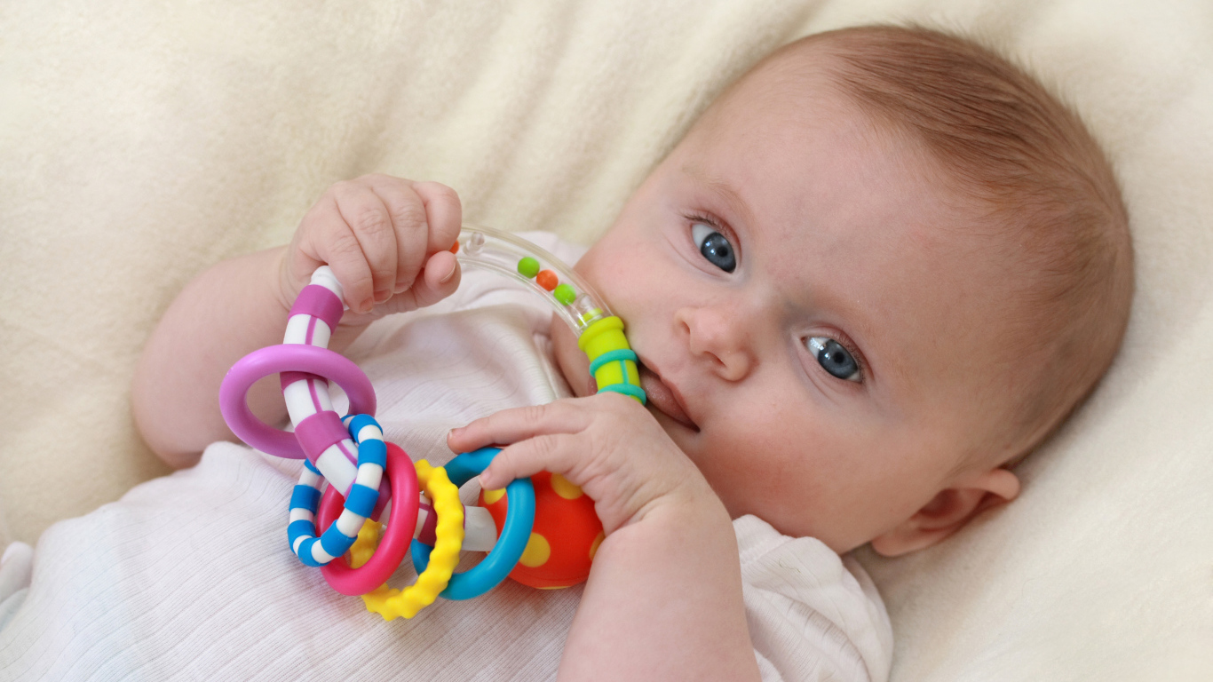 Грудной ребенок с погремушкой в руках