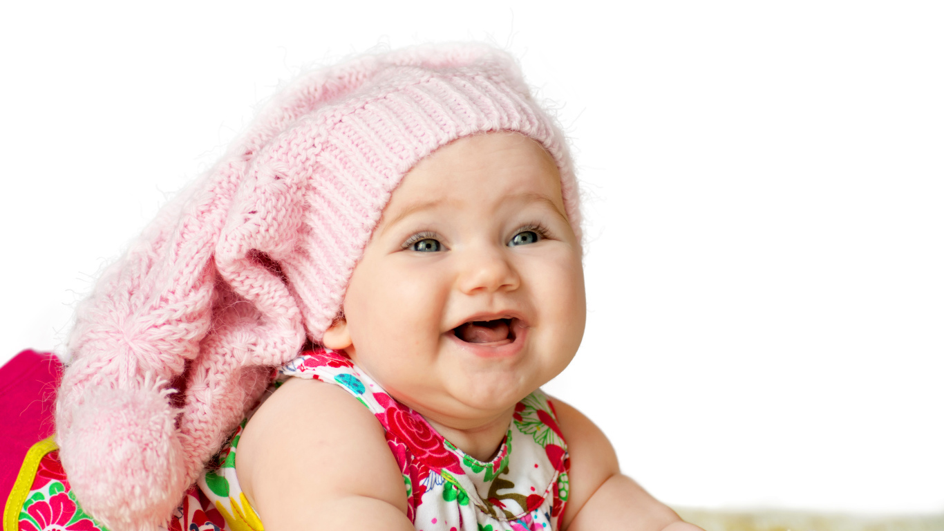 Милая маленькая улыбающаяся девочка в большой розовой шапке