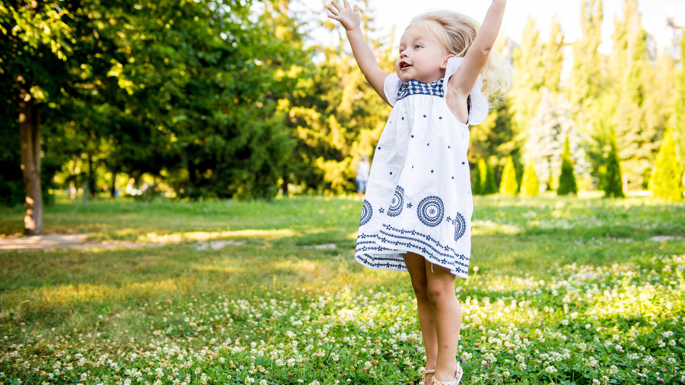 Девочка в красивом платье гуляет на зеленом лугу