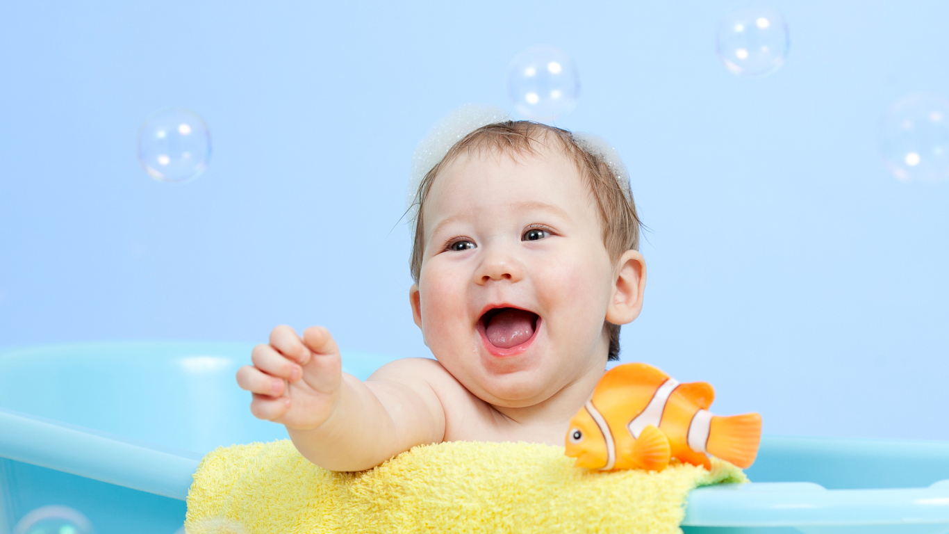 Веселый малыш купается в ванной с игрушечной рыбкой